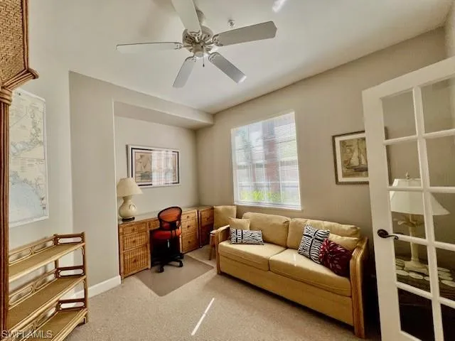 Office space featuring light carpet, baseboards, and a ceiling fan