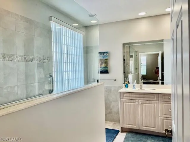 Full bathroom with tile walls, walk in shower, recessed lighting, vanity, and tile patterned flooring