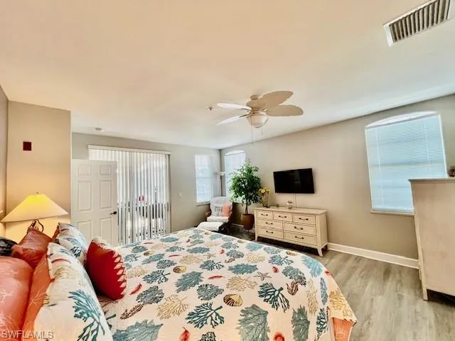 Bedroom with baseboards, access to exterior, light wood-style floors, visible vents, and a ceiling fan