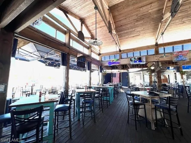 Dining space with beamed ceiling, high vaulted ceiling, wooden ceiling, and hardwood / wood-style flooring