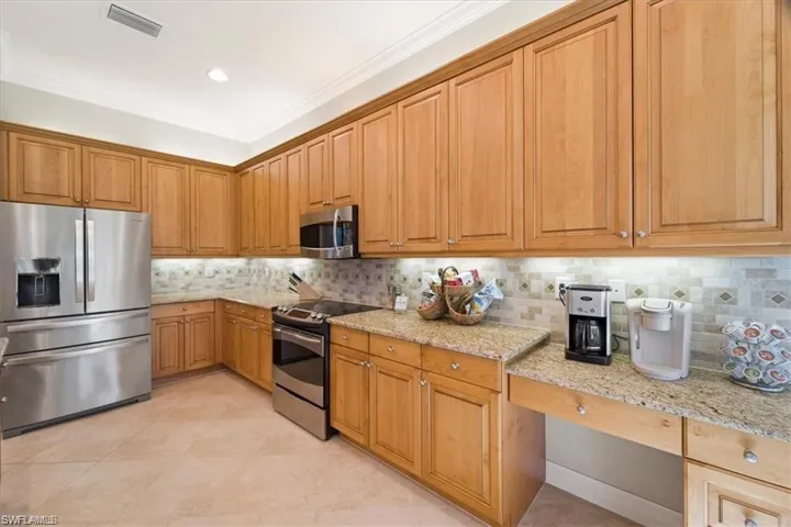 Kitchen featuring stainless steel appliances, backsplash, light stone counters, ornamental molding, and recessed lighting