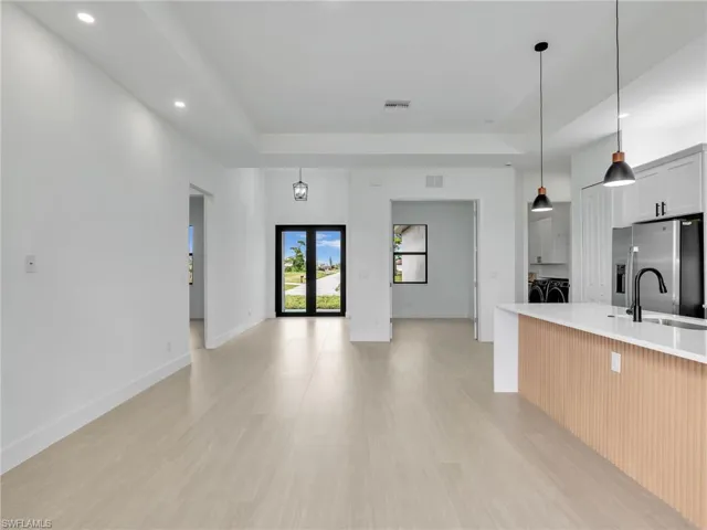 Kitchen featuring a tray ceiling, hanging light fixtures, washing machine and dryer, recessed lighting, and stainless steel refrigerator with ice dispenser