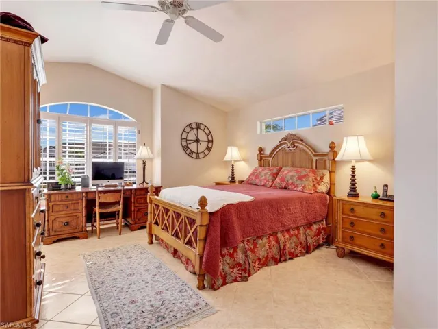 Bedroom with light tile patterned floors, vaulted ceiling, a closet, and ceiling fan
