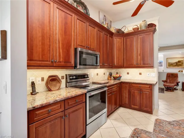 Kitchen with 42" custom Walnut cabinetry, backsplash, stainless steel appliances, granite countertops, decorative light fixtures