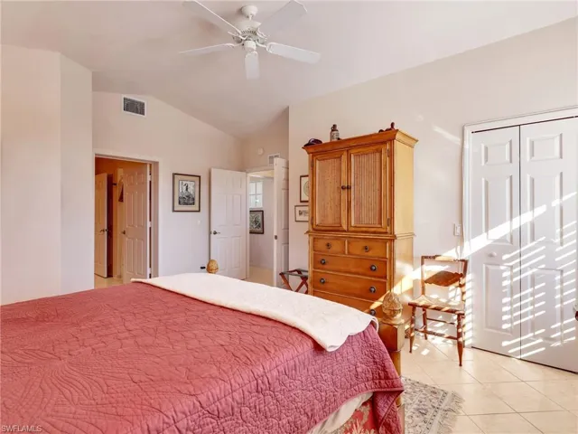Ensuite bathroom with a shower with shower curtain, vanity, light tile patterned flooring, ceiling fan, and vaulted ceiling