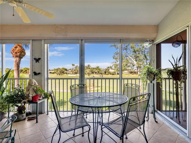 Lanai featuring electric storm shutters, golf course and water views view, and tile patterned floors