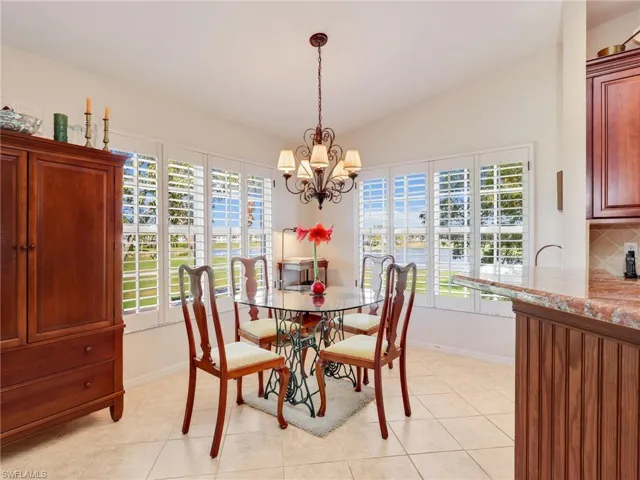 Dining area with lofted ceiling, ceiling fan, light tile patterned flooring, and a chandelier