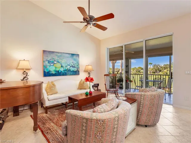 Living area with ceiling fan, light tile patterned flooring, and lofted ceiling