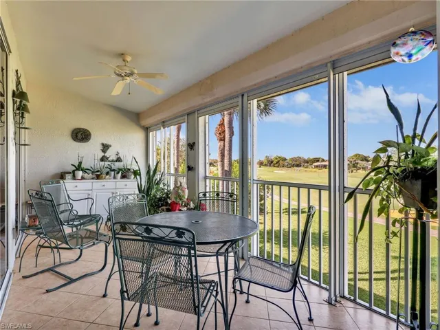 Sunroom featuring vaulted ceiling, tile patterned flooring, a water view, and a ceiling fan
