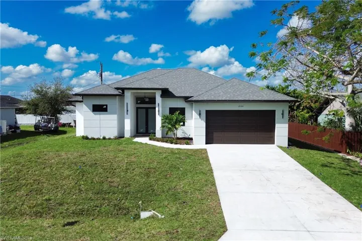 View of front of home with a garage and a front lawn