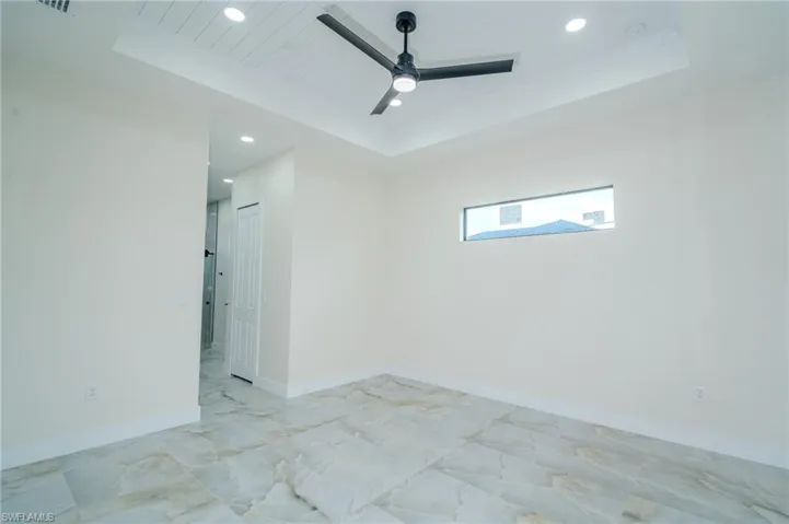 Empty room featuring ceiling fan and a tray ceiling
