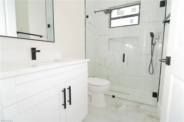 Bathroom featuring toilet, vanity, and an enclosed shower