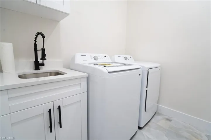 Clothes washing area featuring cabinets, sink, and washing machine and clothes dryer