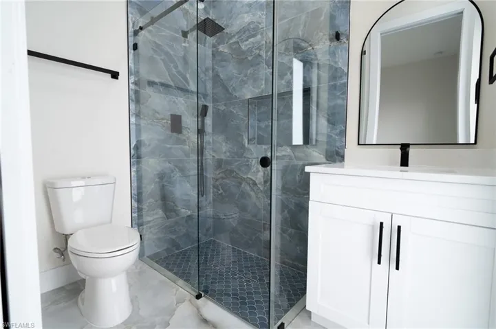 Bathroom featuring toilet, an enclosed shower, and vanity