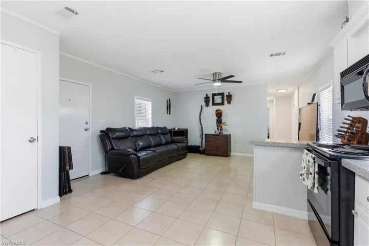 Open-concept living space featuring neutral tile flooring, a ceiling fan, and light gray wall tones