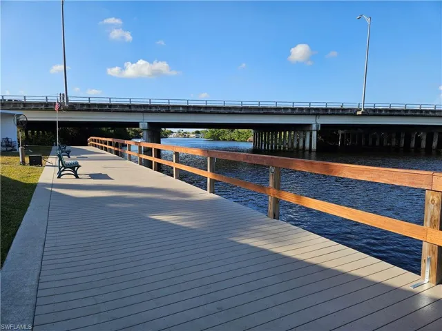 Waterfront boardwalk featuring a concrete surface, wood railing, and integrated seating