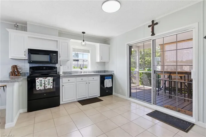 Kitchen featuring white cabinetry, grey speckled countertops, tile flooring, and sliding glass doors to the exterior