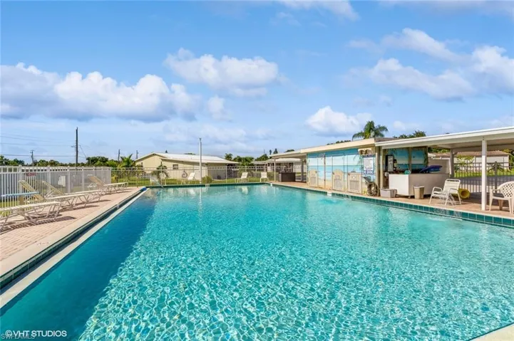 Expansive outdoor heated swimming pool with a tiled perimeter and surrounding concrete decking