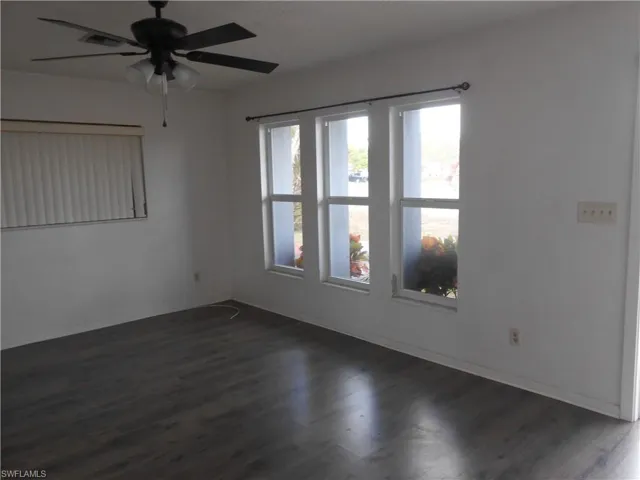 Unfurnished room featuring ceiling fan and dark wood finished floors