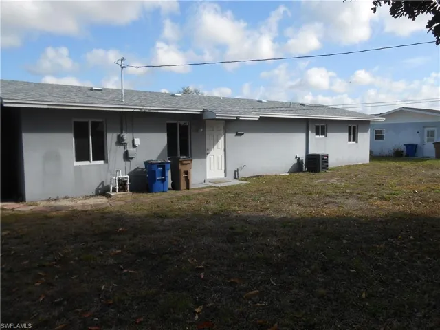 Back of house with a yard, a shingled roof, and stucco siding