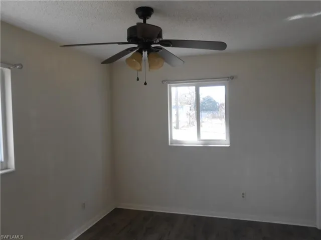 Unfurnished room featuring a textured ceiling, dark wood-type flooring, and ceiling fan
