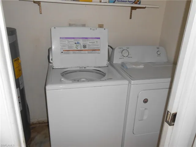 Laundry area with water heater, washing machine and clothes dryer, and concrete flooring