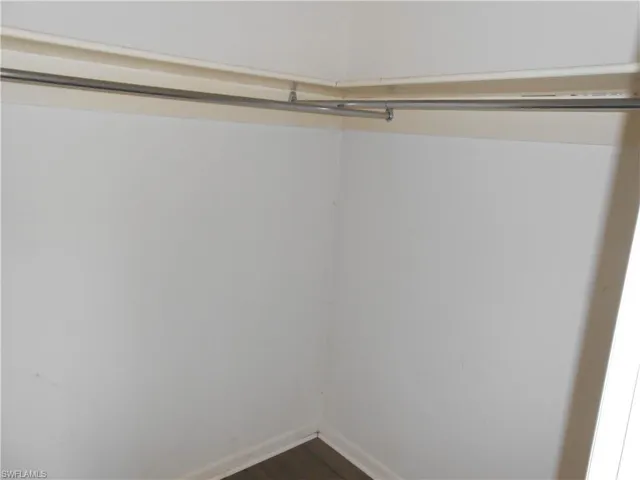 Walk in closet with dark wood-style flooring