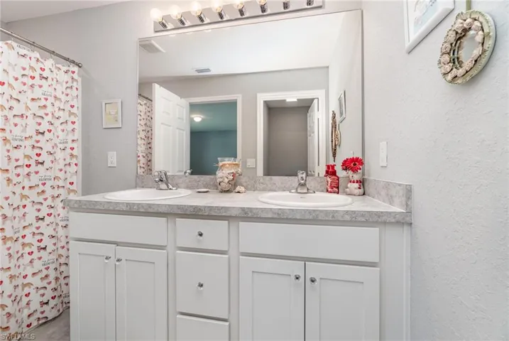 Bathroom featuring dual vanity, shower and separate water closet