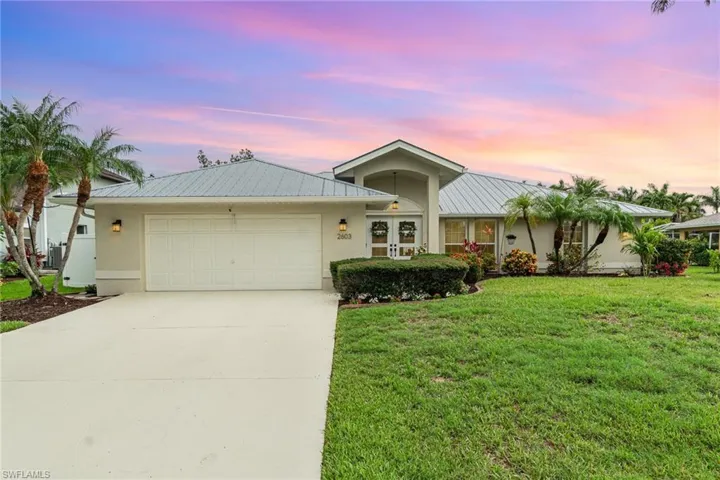 Ranch-style home with stucco siding, metal roof, an attached garage, and concrete driveway