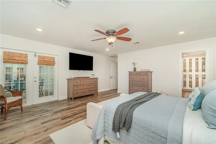 Primary Bedroom featuring french doors, ornamental molding, light wood finished floors, recessed lighting, and access to exterior