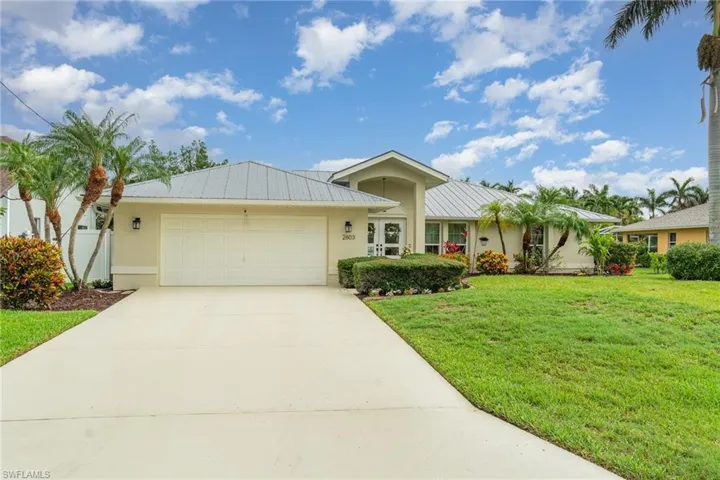 Florida Ranch-style house with a 2 car attached garage, stucco siding, a metal roof, and a front yard