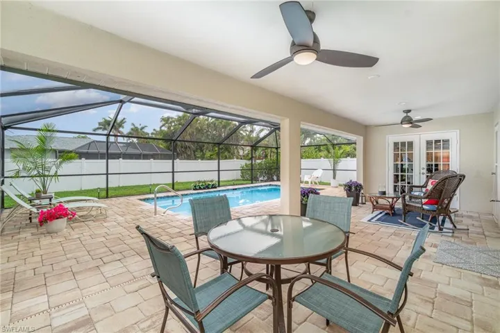Fenced backyard, large covered lanai featuring french doors, ceiling fan, a patio, outdoor dining area, and even sun lounge area