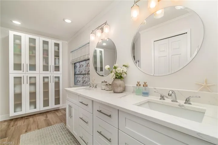 Full ensuite bath with crown molding, double vanity, recessed lighting, and wood finished floors