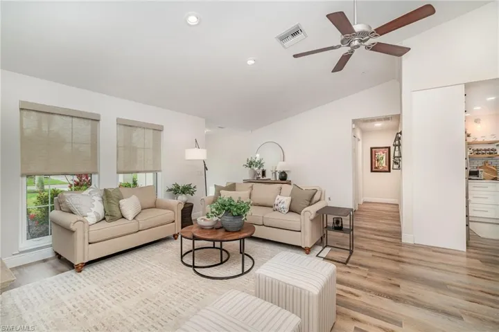 Living area featuring light LVP wood-style floors, vaulted ceiling, a ceiling fan, recessed lighting, and baseboards