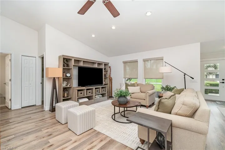 Living area with plenty of natural light, light LVP wood finished floors, ceiling fan, recessed lighting, and high vaulted ceiling