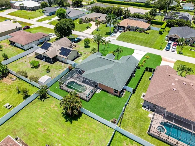 Residential property featuring a screened-in pool, manicured lawn, and mature palm trees