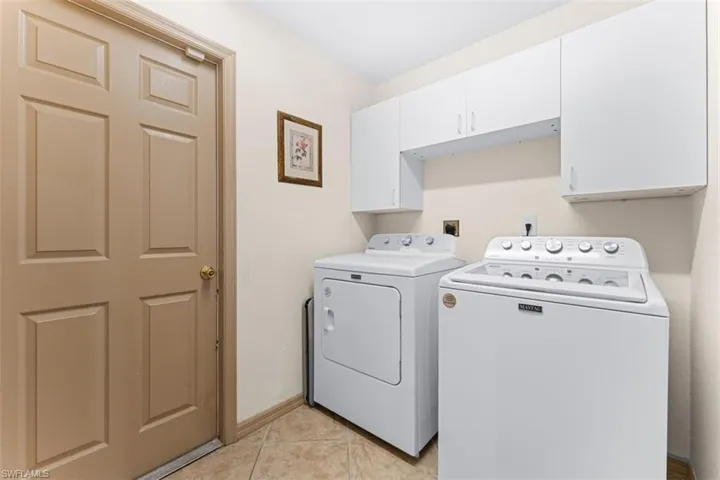 Functional utility area featuring white cabinetry providing overhead storage
