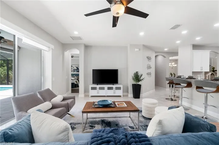 Tiled living room featuring sink and ceiling fan with notable chandelier