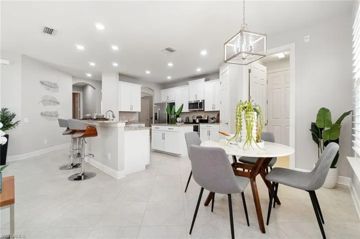 Light and bright Eat-in Dining room with light tile patterned flooring, sink, and a chandelier