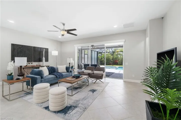 Tiled oversized open great room with ceiling fan leads out to newer pool deck and saltwater system pool and spa