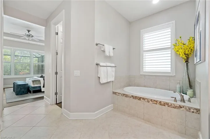 Primary suite offers plenty of natural light, filtered with plantation shutters