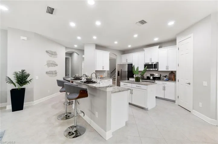 Kitchen with light tile patterned flooring, a breakfast bar area, light stone countertops, appliances with stainless steel finishes, and island offering extra work space
