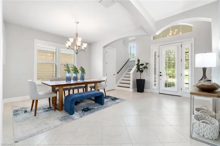 Tiled dining area featuring an inviting chandelier and vaulted ceiling