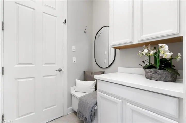 Mudroom at owners entry off the garage with convenient bench and custom white cabinetry with white quartz counters.