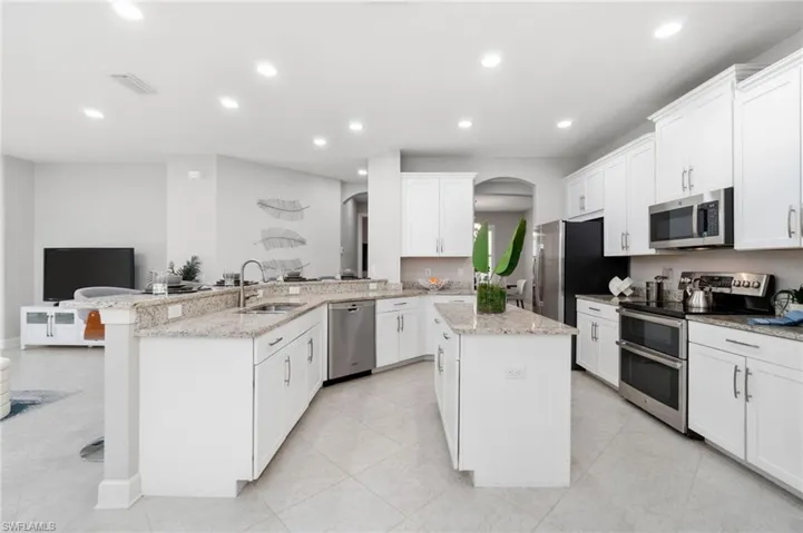 Kitchen with stainless steel appliances, light granite countertops and center island offering extra workspace