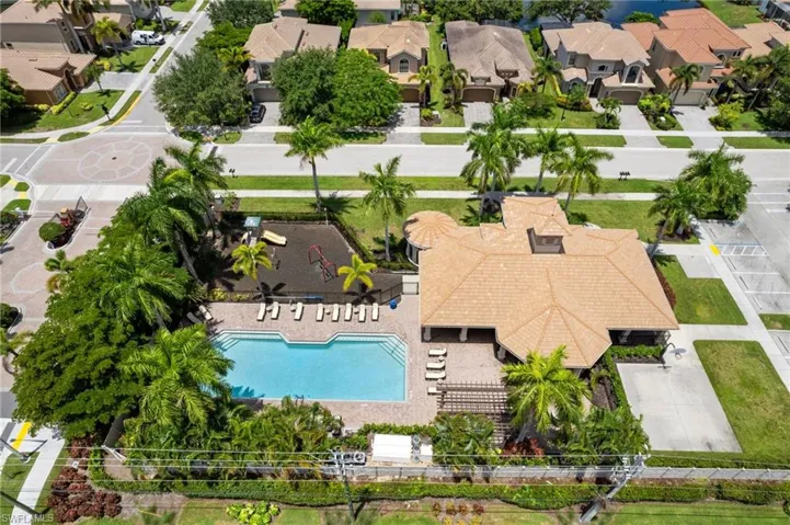Aerial view of community pool, clubhouse, playground area and activity courts.