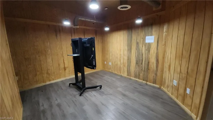 Exercise room with wood finished floors, wood walls, and baseboards