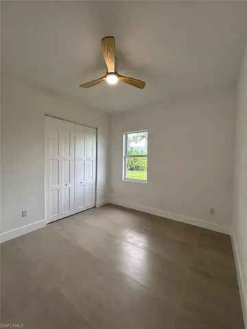 Unfurnished bedroom featuring ceiling fan, tile patterned floors, and a closet