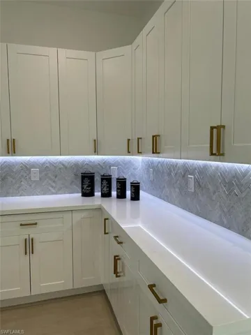 Kitchen with light wood-type flooring, white cabinets, and backsplash