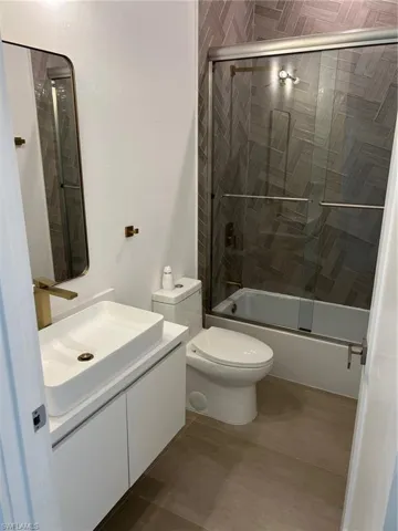 Full bathroom with shower / bath combination with glass door, vanity, and toilet